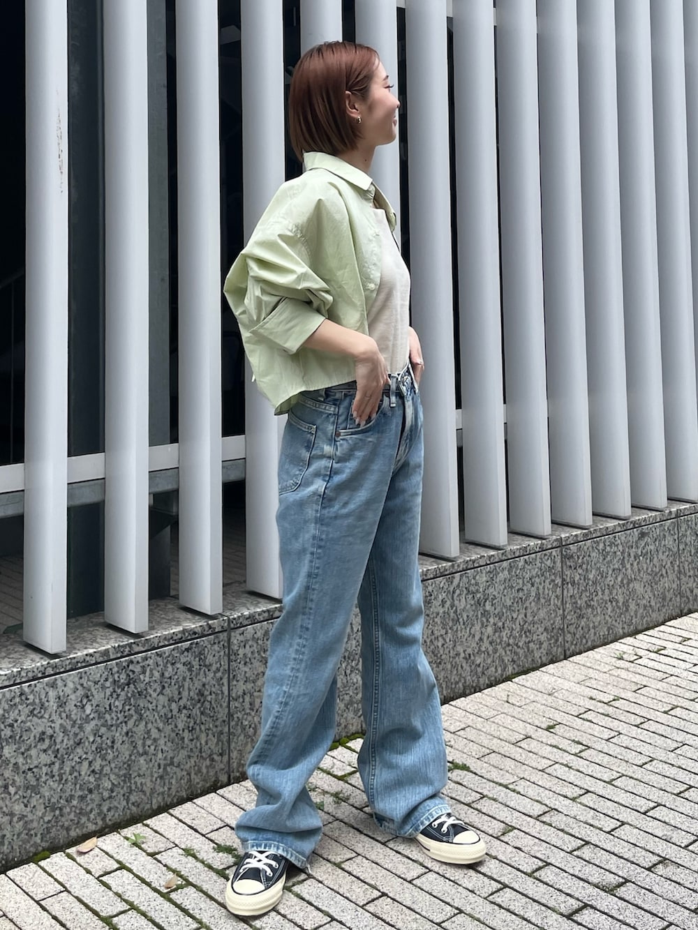 グリーン系のシャツ/ブラウス、ホワイト系のキャミソール、ブルー系のデニムパンツを着用したレディースの春コーディネートの3枚目の写真