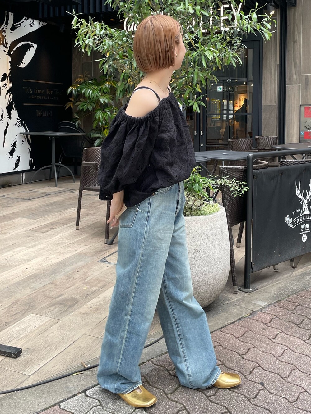 ブラック系のシャツ/ブラウス、ブルー系のデニムパンツ、ゴールド系のパンプスを着用したレディースの春コーディネートの3枚目の写真