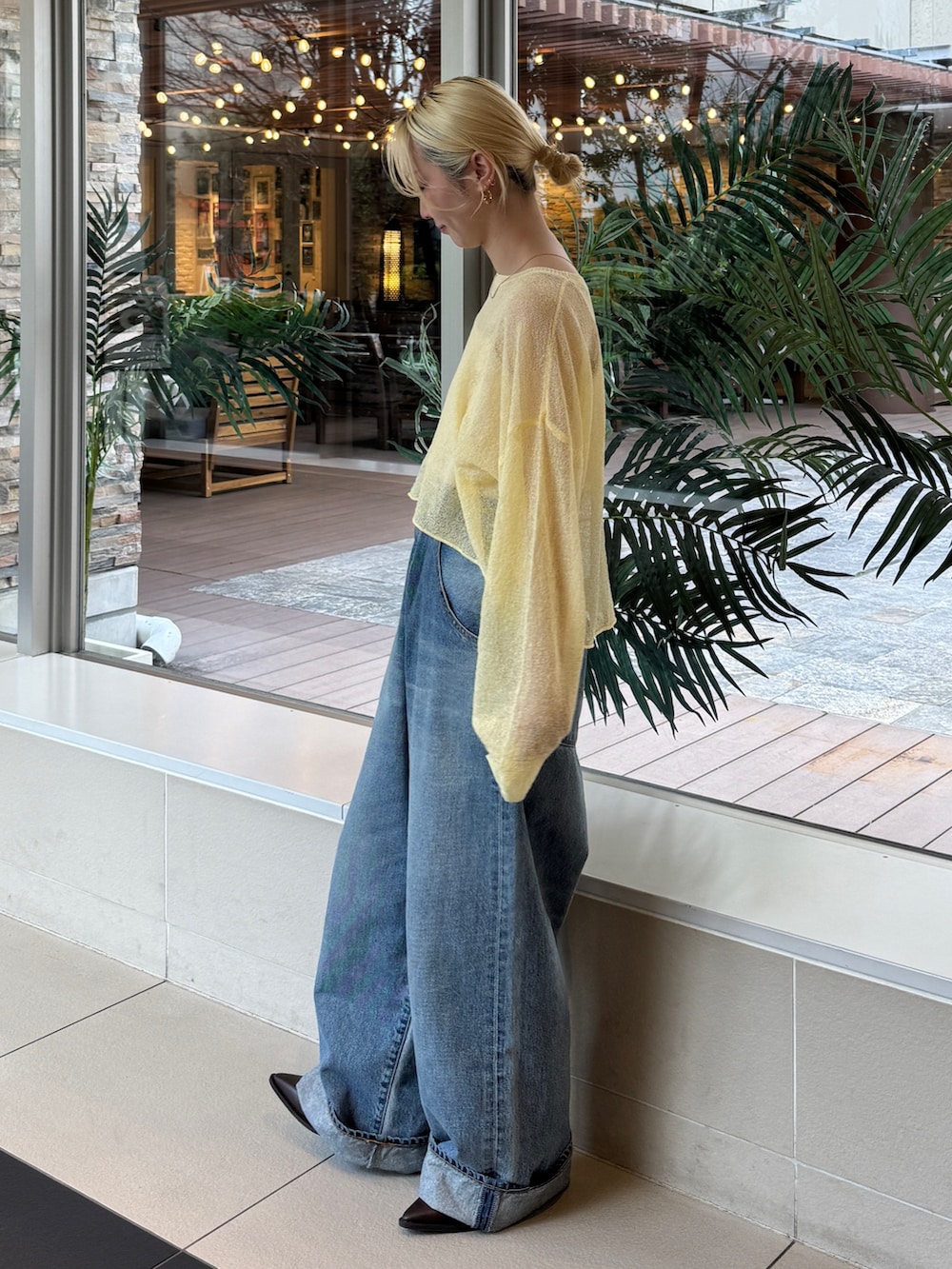 イエロー系のニット/セーター、ブルー系のデニムパンツを着用したレディースの冬コーディネートの2枚目の写真