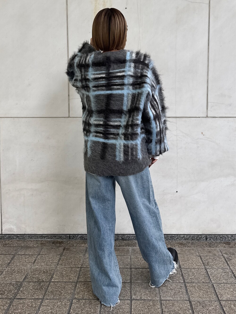 グレー系のニット/セーター、ホワイト系のTシャツ/カットソー、ブルー系のデニムパンツを着用したレディースの秋コーディネートの4枚目の写真