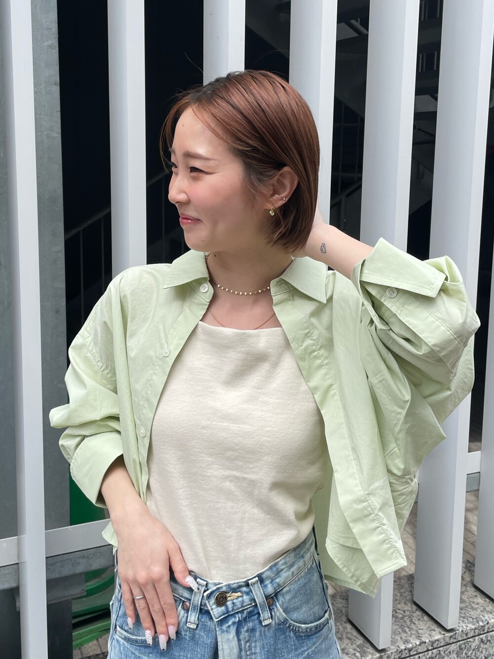 グリーン系のシャツ/ブラウス、ホワイト系のキャミソール、ブルー系のデニムパンツを着用したレディースの春コーディネートの4枚目の写真