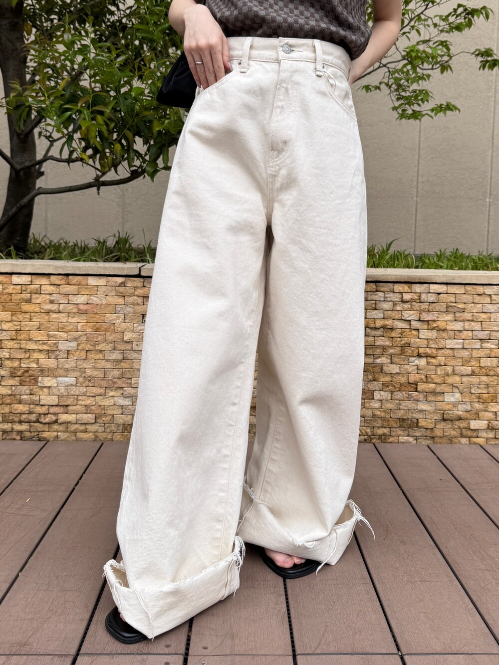 ブラウン系のタンクトップ、ホワイト系のデニムパンツ、ブラック系のサンダルを着用したレディースの春コーディネートの8枚目の写真