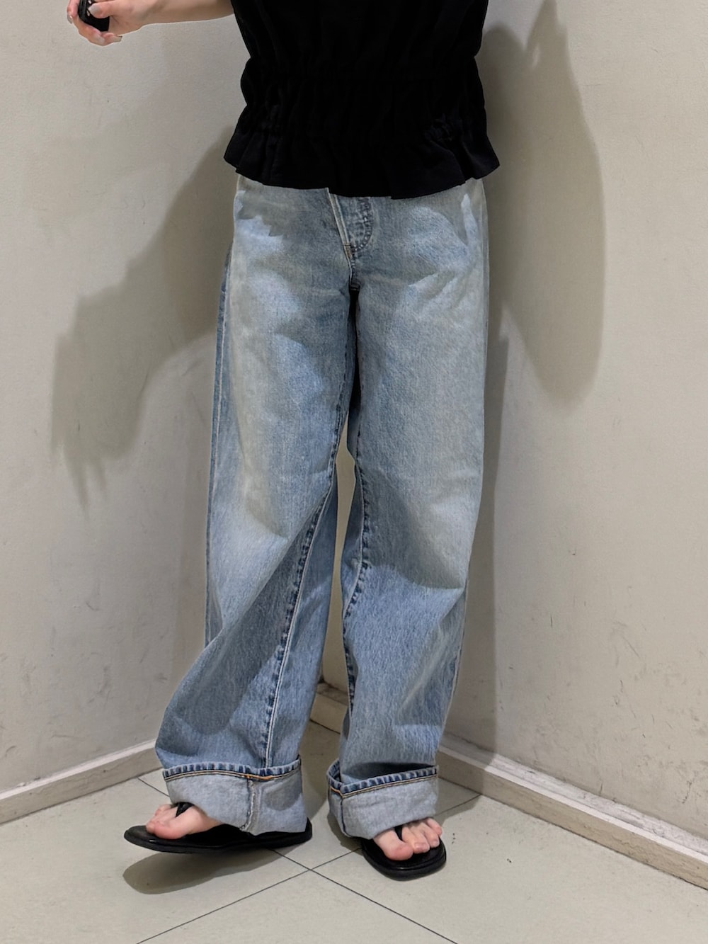 ブラック系のタンクトップ、ブルー系のデニムパンツ、ブラック系のサンダルを着用したレディースの春コーディネートの7枚目の写真