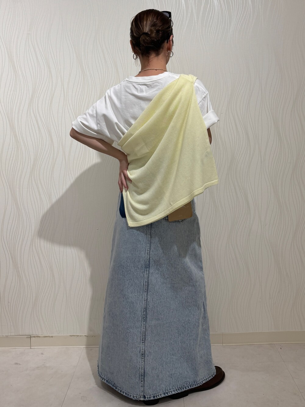 ホワイト系のTシャツ/カットソー、イエロー系のニット/セーター、ブルー系のスカートを着用したレディースの春コーディネートの3枚目の写真