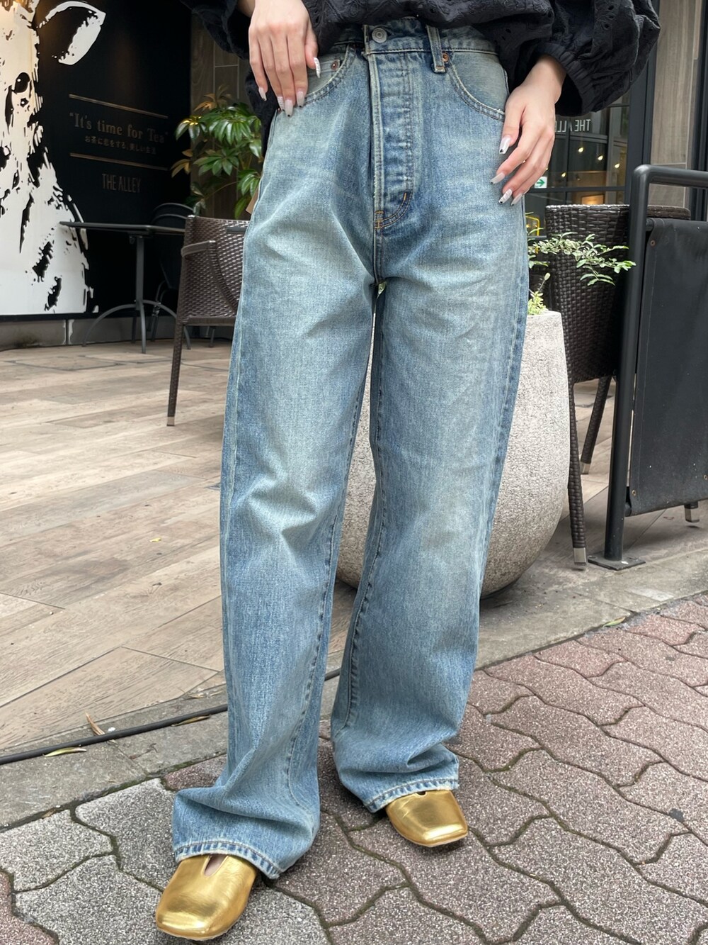 ブラック系のシャツ/ブラウス、ブルー系のデニムパンツ、ゴールド系のパンプスを着用したレディースの春コーディネートの5枚目の写真