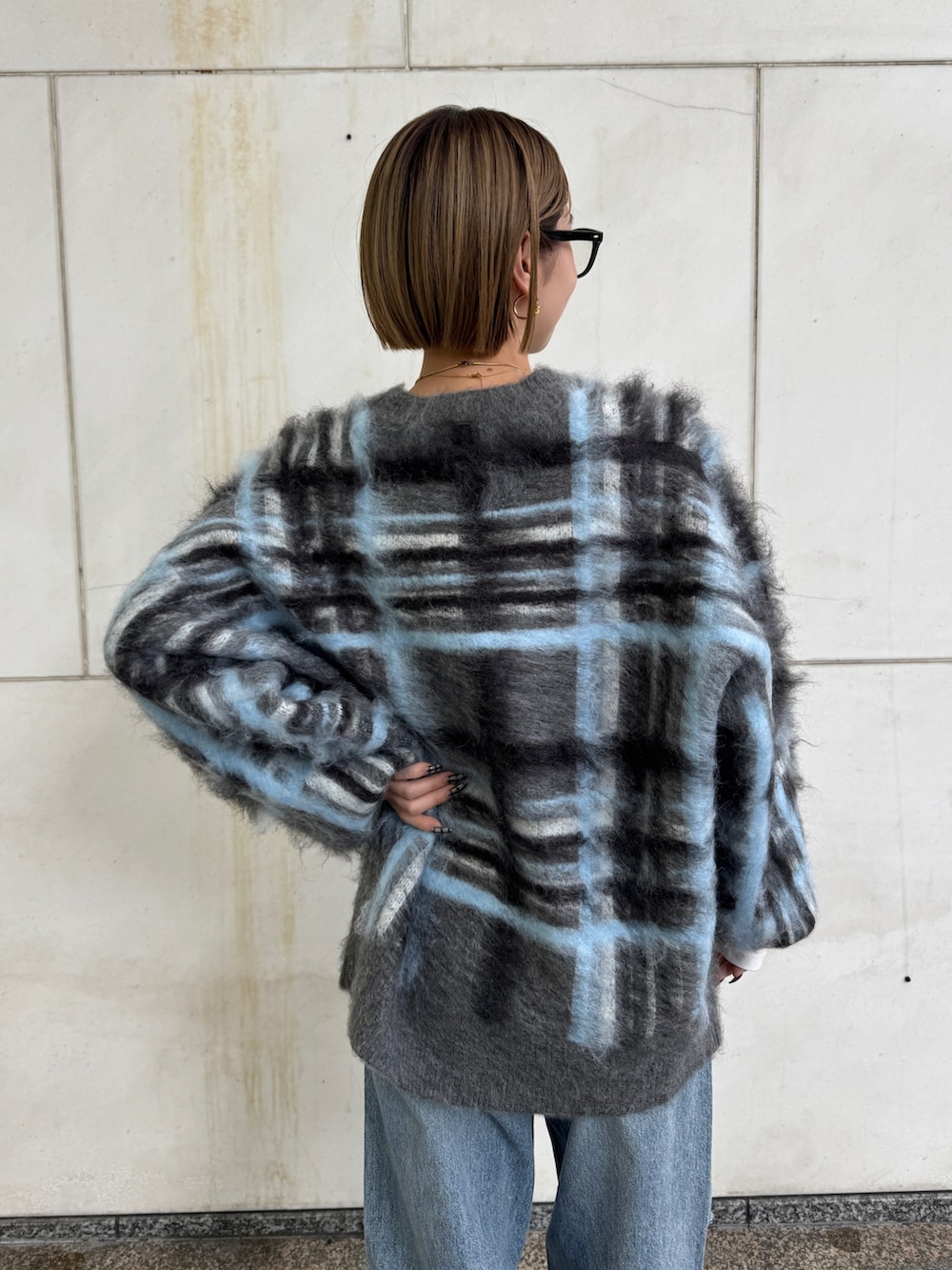 グレー系のニット/セーター、ホワイト系のTシャツ/カットソー、ブルー系のデニムパンツを着用したレディースの秋コーディネートの7枚目の写真