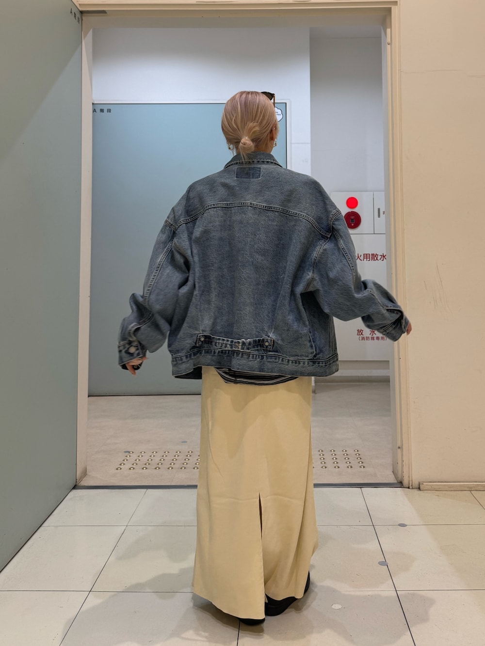 グレー系のTシャツ/カットソー、ブルー系のデニムジャケット、イエロー系のスカートを着用したレディースの冬コーディネートの3枚目の写真