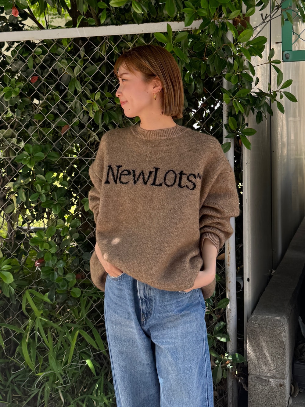 ブラック系のスニーカー、ベージュ系のニット/セーター、ブルー系のデニムパンツを着用したレディースの夏コーディネートの4枚目の写真