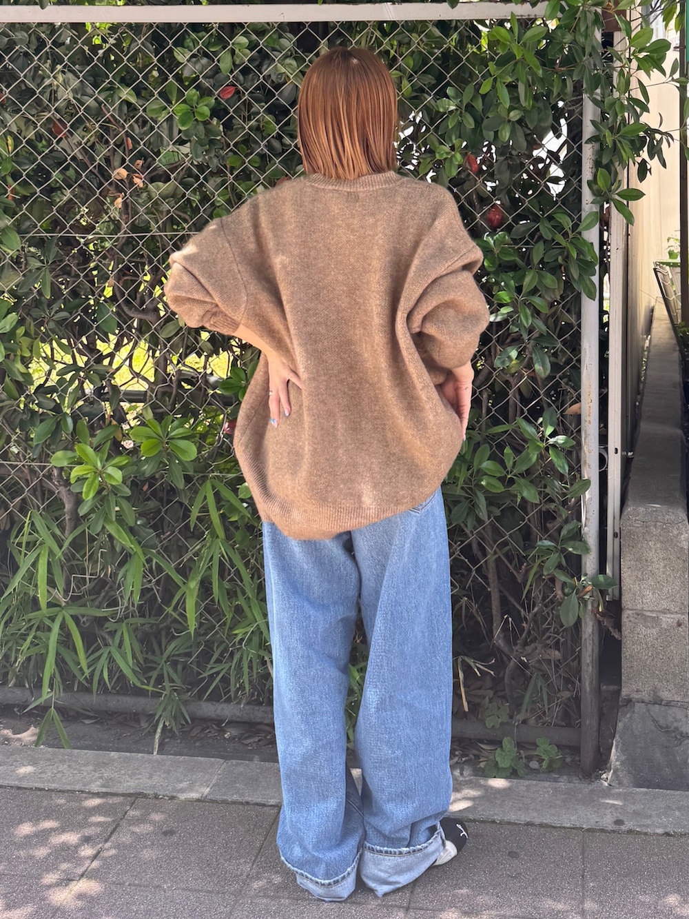 ブラック系のスニーカー、ベージュ系のニット/セーター、ブルー系のデニムパンツを着用したレディースの夏コーディネートの3枚目の写真