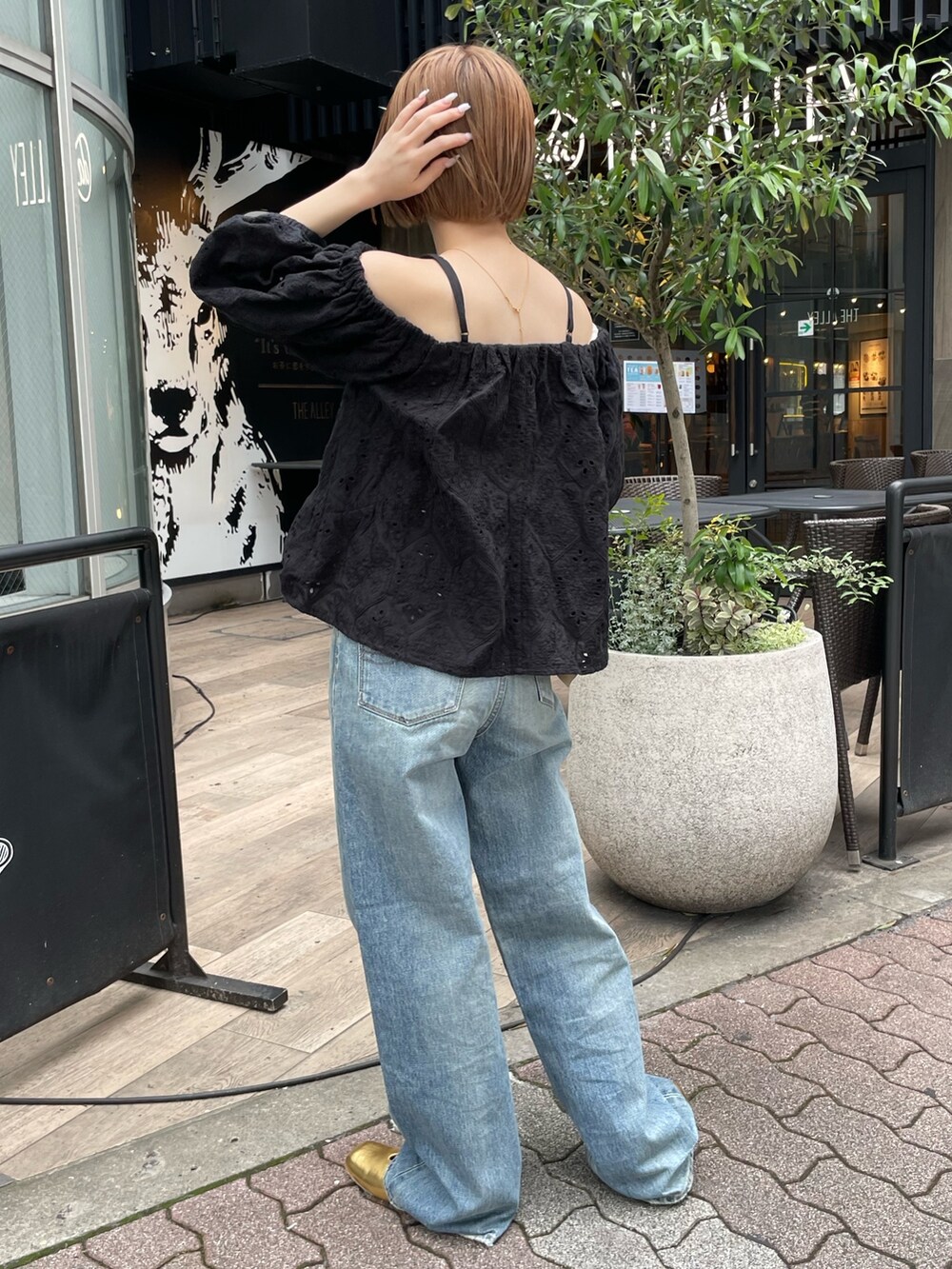 ブラック系のシャツ/ブラウス、ブルー系のデニムパンツ、ゴールド系のパンプスを着用したレディースの春コーディネートの2枚目の写真