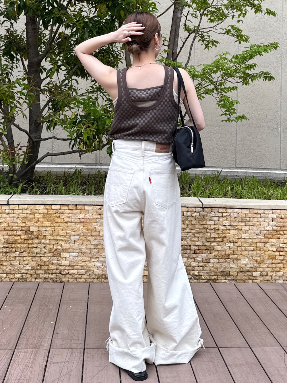 ブラウン系のタンクトップ、ホワイト系のデニムパンツ、ブラック系のサンダルを着用したレディースの春コーディネートの3枚目の写真