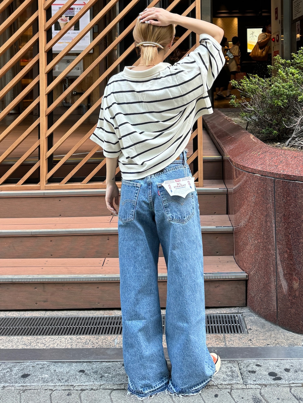 ホワイト系のポロシャツ、オレンジ系のスニーカー、ブルー系のデニムパンツを着用したレディースの夏コーディネートの3枚目の写真