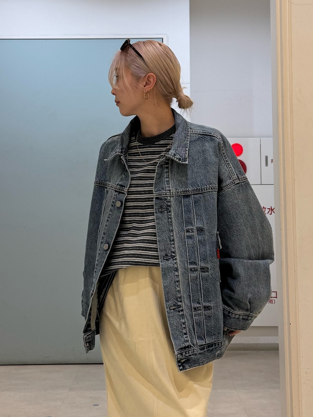 グレー系のTシャツ/カットソー、ブルー系のデニムジャケット、イエロー系のスカートを着用したレディースの冬コーディネートの4枚目の写真