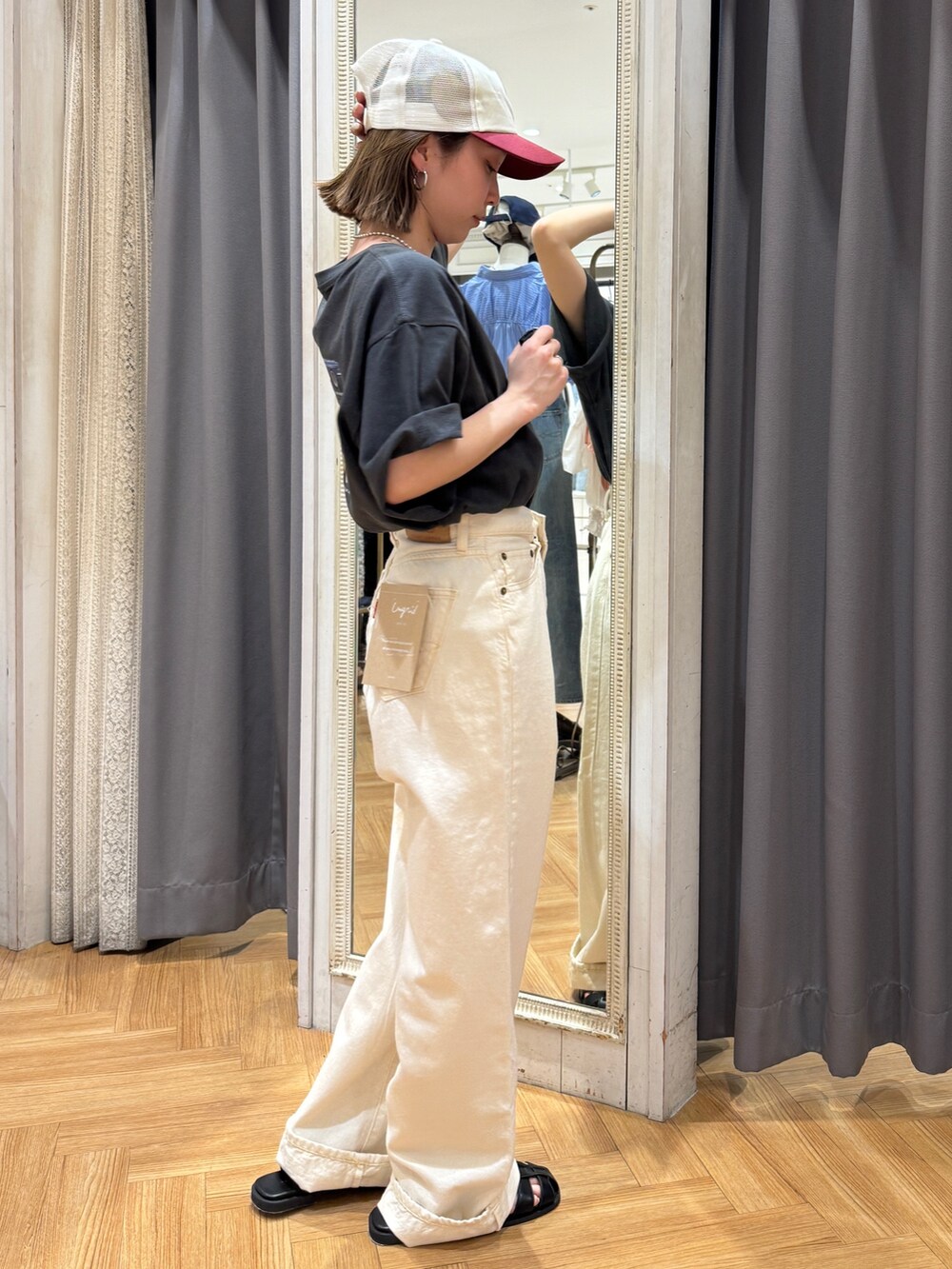 グレー系のTシャツ/カットソー、ホワイト系のデニムパンツ、ブラック系のサンダルを着用したレディースの春コーディネートの2枚目の写真