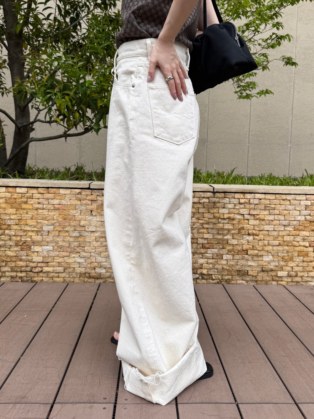 ブラウン系のタンクトップ、ホワイト系のデニムパンツ、ブラック系のサンダルを着用したレディースの春コーディネートの9枚目の写真