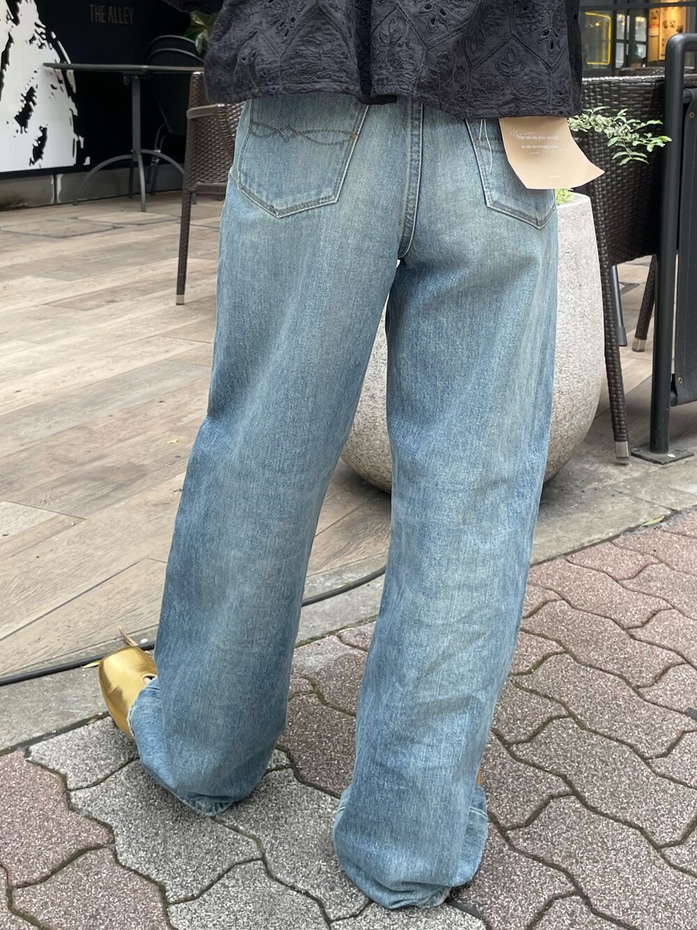 ブラック系のシャツ/ブラウス、ブルー系のデニムパンツ、ゴールド系のパンプスを着用したレディースの春コーディネートの6枚目の写真