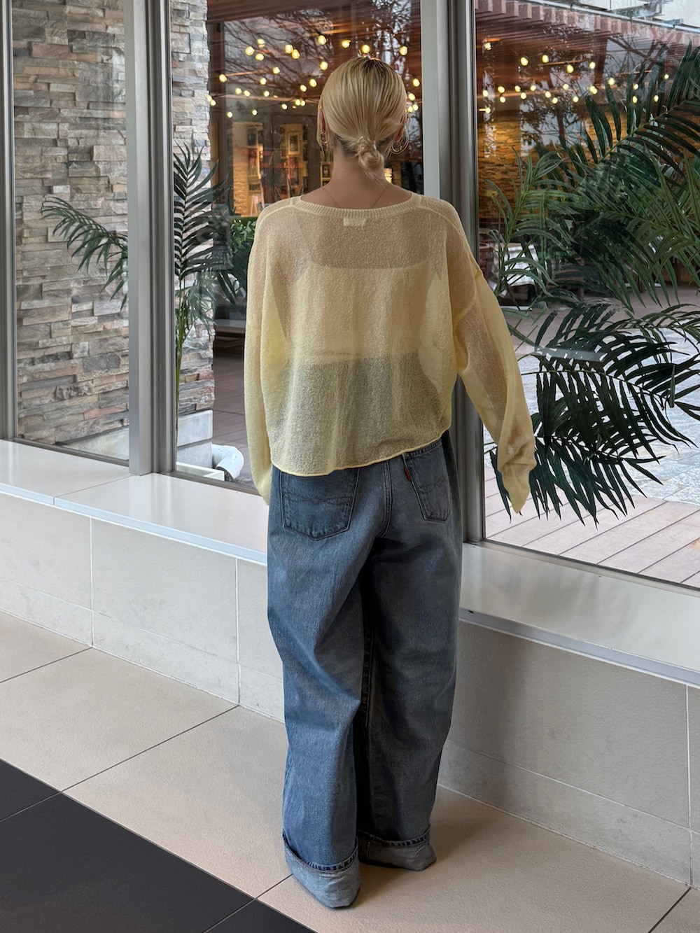 イエロー系のニット/セーター、ブルー系のデニムパンツを着用したレディースの冬コーディネートの3枚目の写真