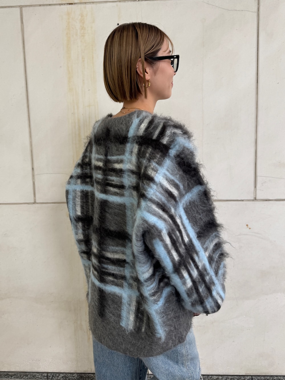 グレー系のニット/セーター、ホワイト系のTシャツ/カットソー、ブルー系のデニムパンツを着用したレディースの秋コーディネートの6枚目の写真