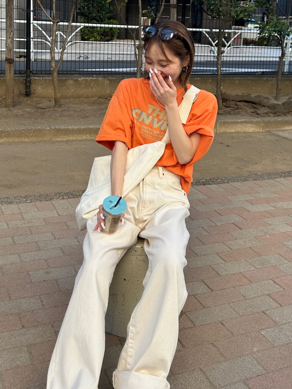 オレンジ系のTシャツ/カットソー、ホワイト系のハンドバッグ、ホワイト系のデニムパンツを着用したレディースの春コーディネートの4枚目の写真