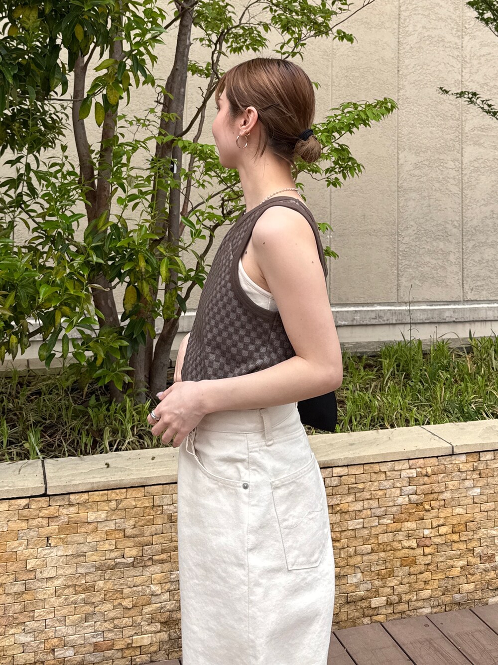 ブラウン系のタンクトップ、ホワイト系のデニムパンツ、ブラック系のサンダルを着用したレディースの春コーディネートの5枚目の写真