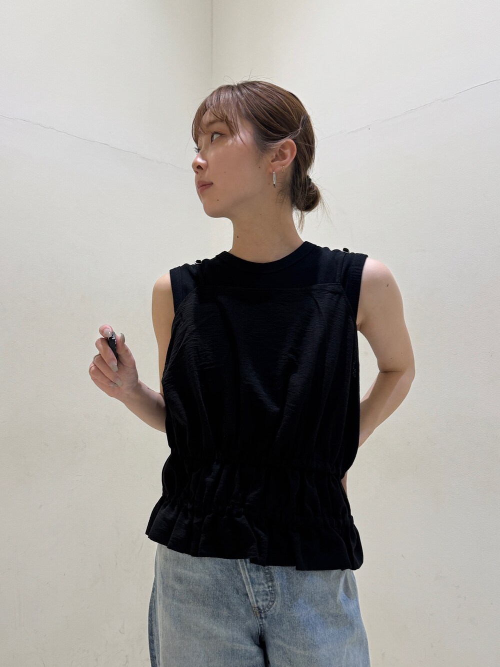 ブラック系のタンクトップ、ブルー系のデニムパンツ、ブラック系のサンダルを着用したレディースの春コーディネートの4枚目の写真