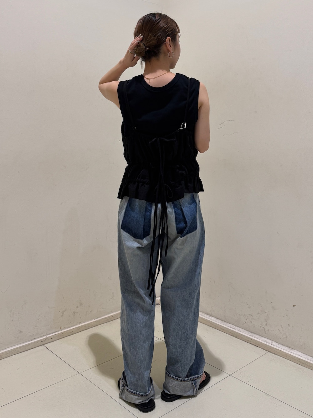 ブラック系のタンクトップ、ブルー系のデニムパンツ、ブラック系のサンダルを着用したレディースの春コーディネートの3枚目の写真