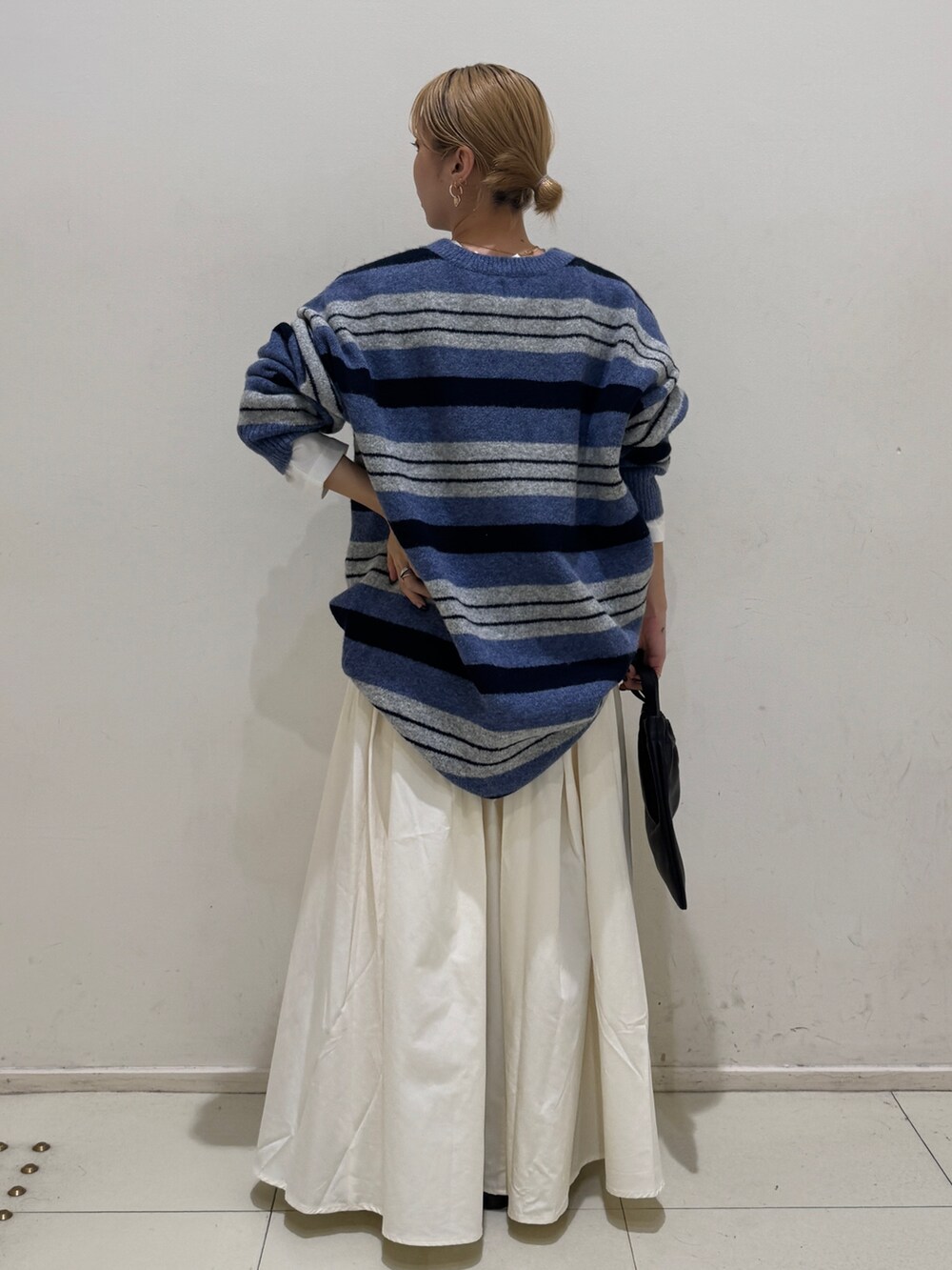 ブルー系のニット/セーター、ホワイト系のTシャツ/カットソー、ホワイト系のスカートを着用したレディースの秋コーディネートの3枚目の写真