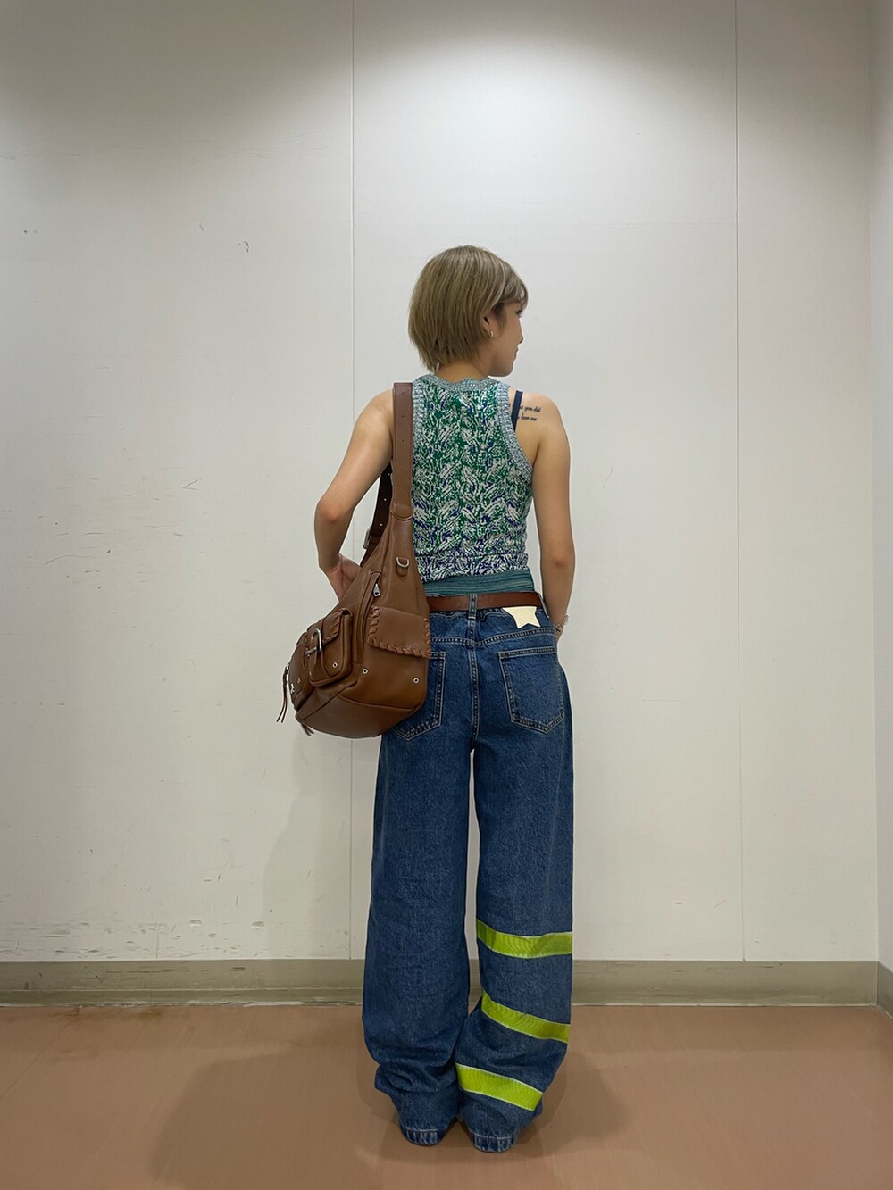 ブルー系のデニムパンツ、グリーン系のタンクトップ、ブラウン系のショルダーバッグを着用したレディースの夏コーディネートの3枚目の写真