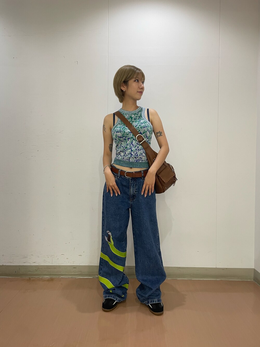 ブルー系のデニムパンツ、グリーン系のタンクトップ、ブラウン系のショルダーバッグを着用したレディースの夏コーディネートの2枚目の写真