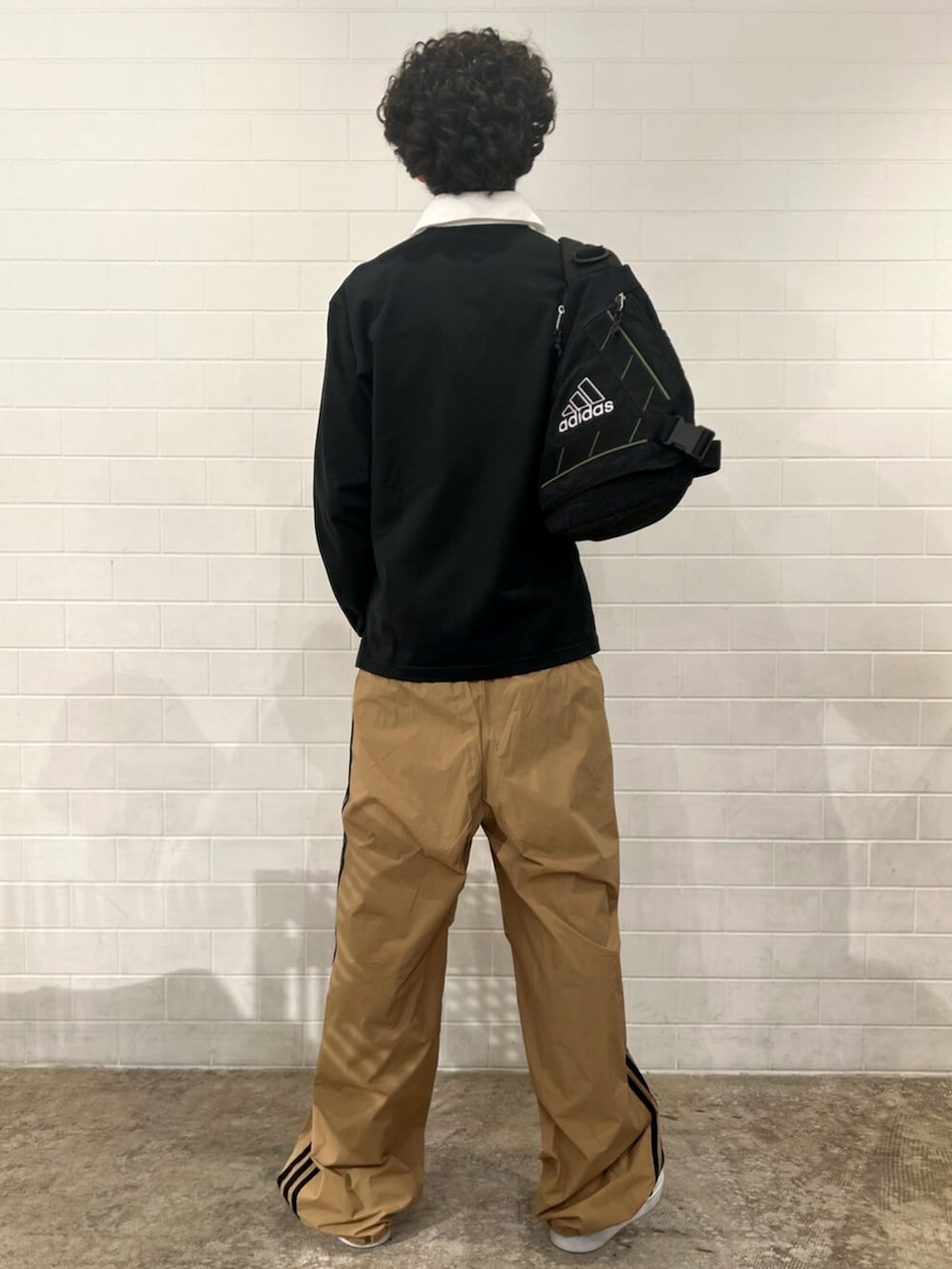 ブラック系のポロシャツ、ブラウン系のその他パンツ、ホワイト系のスニーカーを着用したメンズの秋コーディネートの2枚目の写真