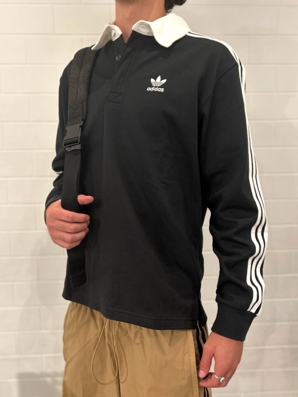 ブラック系のポロシャツ、ブラウン系のその他パンツ、ホワイト系のスニーカーを着用したメンズの秋コーディネートの3枚目の写真