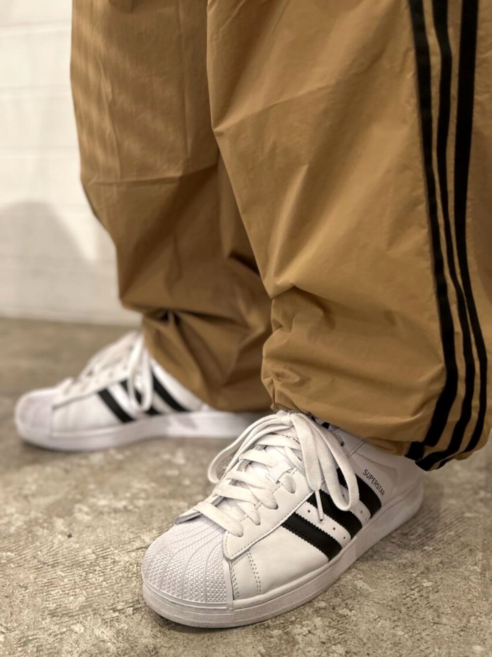 ブラック系のポロシャツ、ブラウン系のその他パンツ、ホワイト系のスニーカーを着用したメンズの秋コーディネートの6枚目の写真