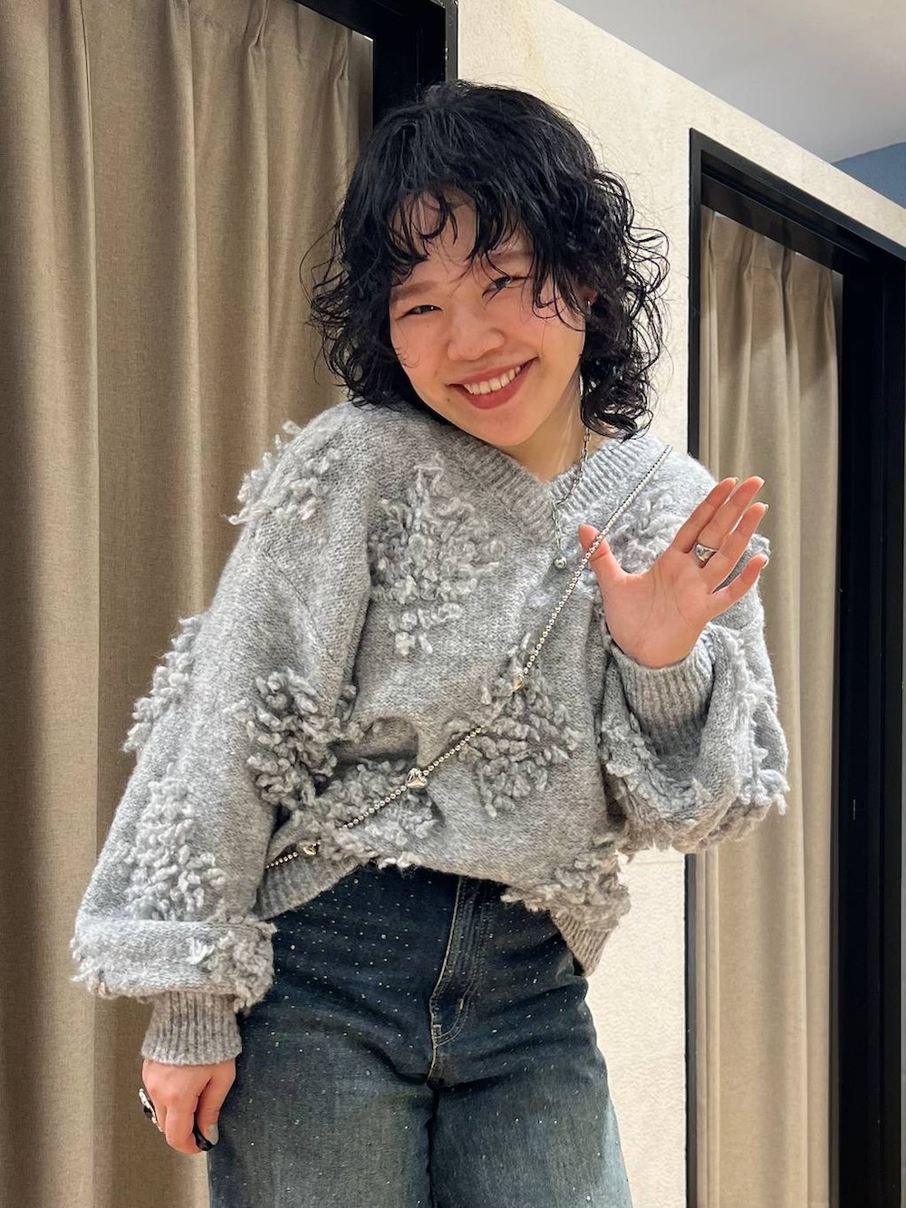 ブルー系のデニムパンツ、グレー系のニット/セーター、グレー系のスマホグッズを着用したレディースの冬コーディネートの2枚目の写真