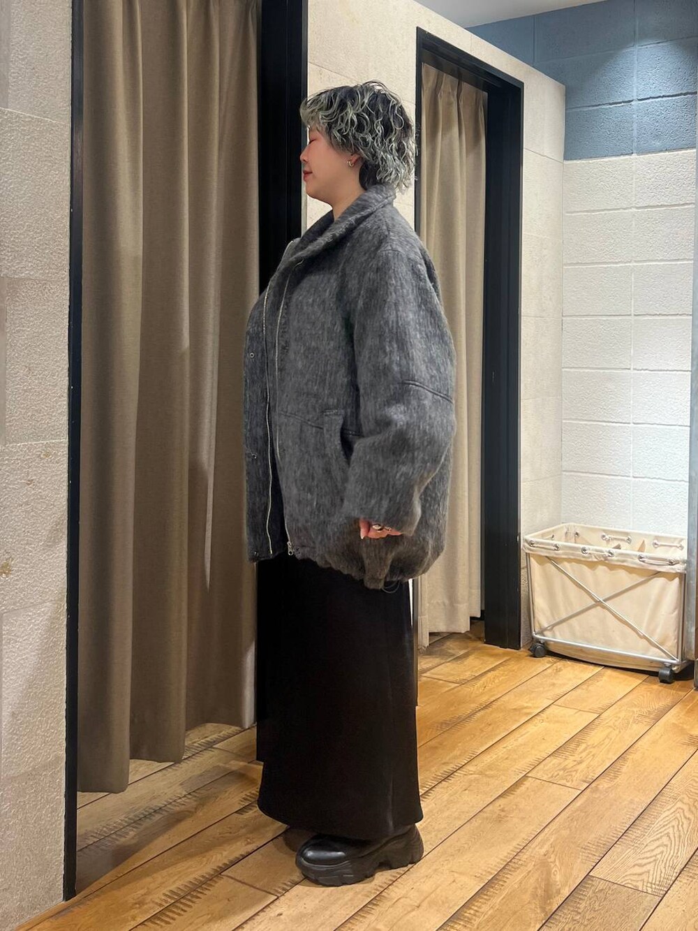 ブラック系のブーツ、ブラック系のスカート、グレー系のその他アウターを着用したレディースの冬コーディネートの2枚目の写真