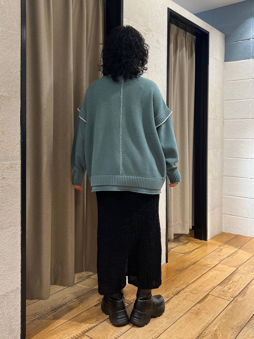 グリーン系のニット/セーター、ブラック系のブーツ、ブラック系のスカートを着用したレディースの秋コーディネートの3枚目の写真