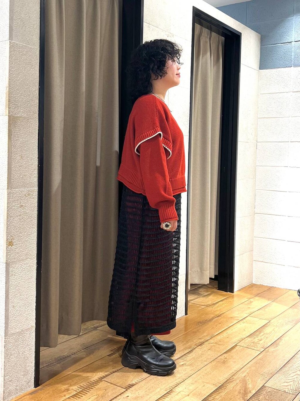 レッド系のニット/セーター、ブラック系のブーツ、ブラック系のワンピースを着用したレディースの秋コーディネートの4枚目の写真