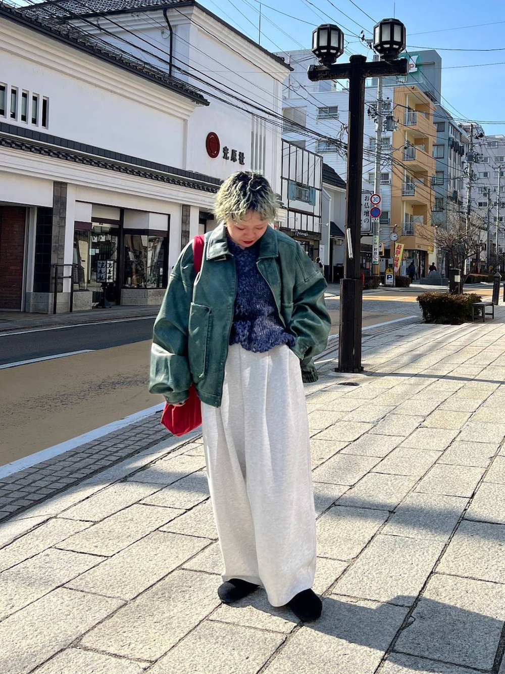 グレー系のスウェットパンツ、グリーン系のブルゾン、シルバー系のネックレスを着用したレディースの春コーディネートの2枚目の写真