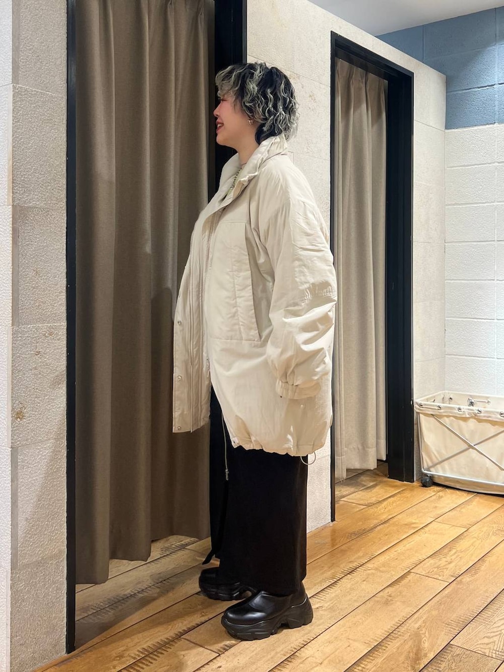 ブラック系のブーツ、ホワイト系のブルゾン、グリーン系のニット/セーターを着用したレディースの冬コーディネートの2枚目の写真