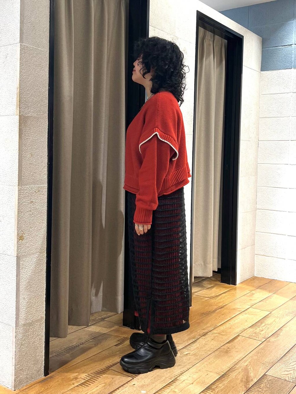 レッド系のニット/セーター、ブラック系のブーツ、ブラック系のワンピースを着用したレディースの秋コーディネートの2枚目の写真
