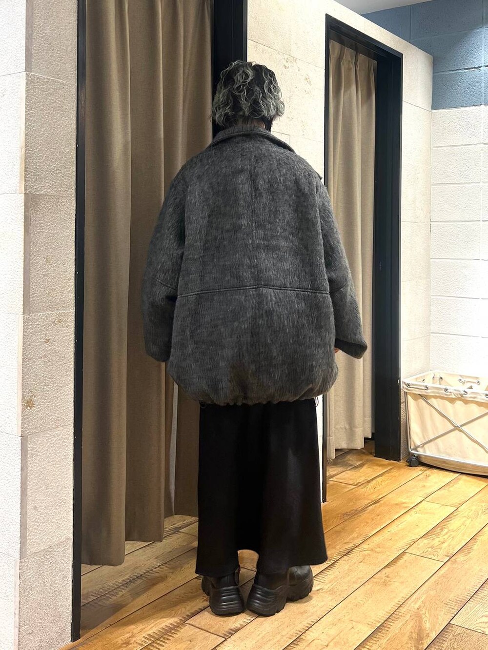 ブラック系のブーツ、ブラック系のスカート、グレー系のその他アウターを着用したレディースの冬コーディネートの3枚目の写真