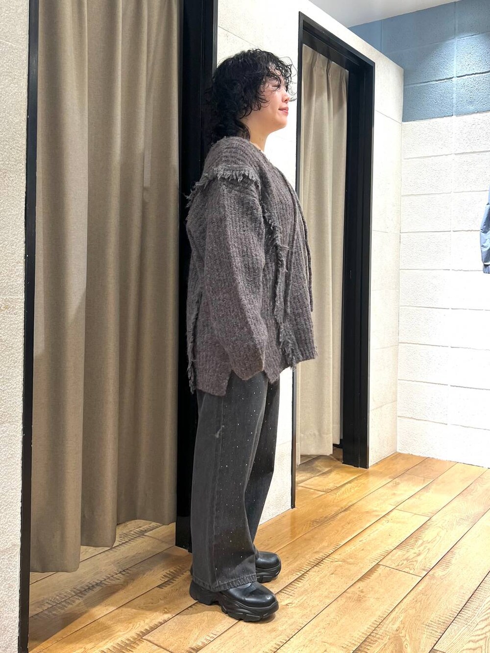 グレー系のニット/セーター、ブラック系のデニムパンツ、ブラック系のブーツを着用したレディースの秋コーディネートの2枚目の写真