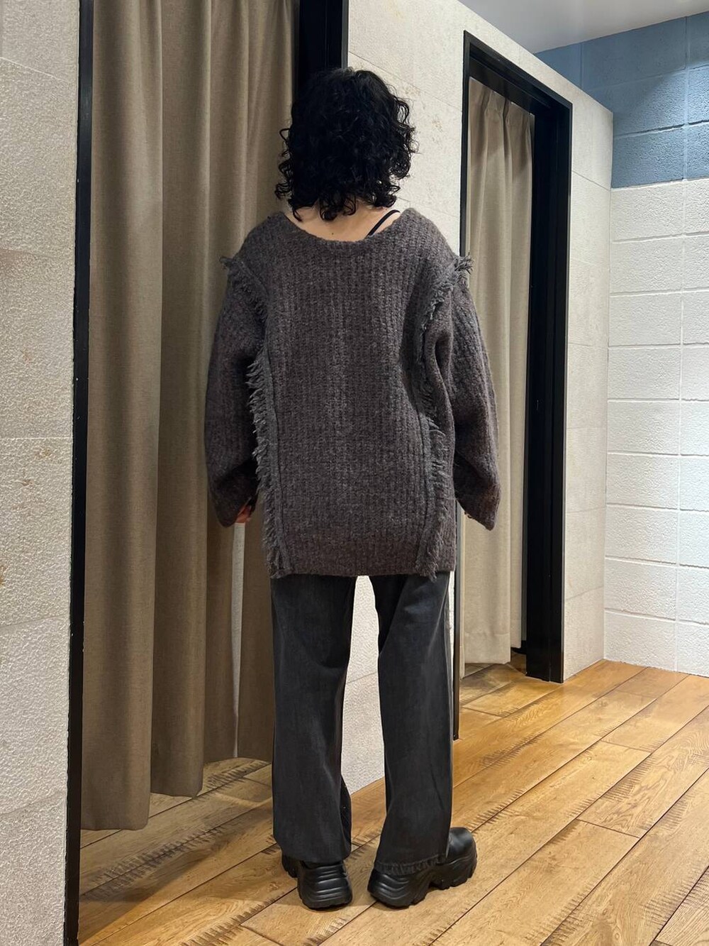 グレー系のニット/セーター、ブラック系のデニムパンツ、ブラック系のブーツを着用したレディースの秋コーディネートの3枚目の写真