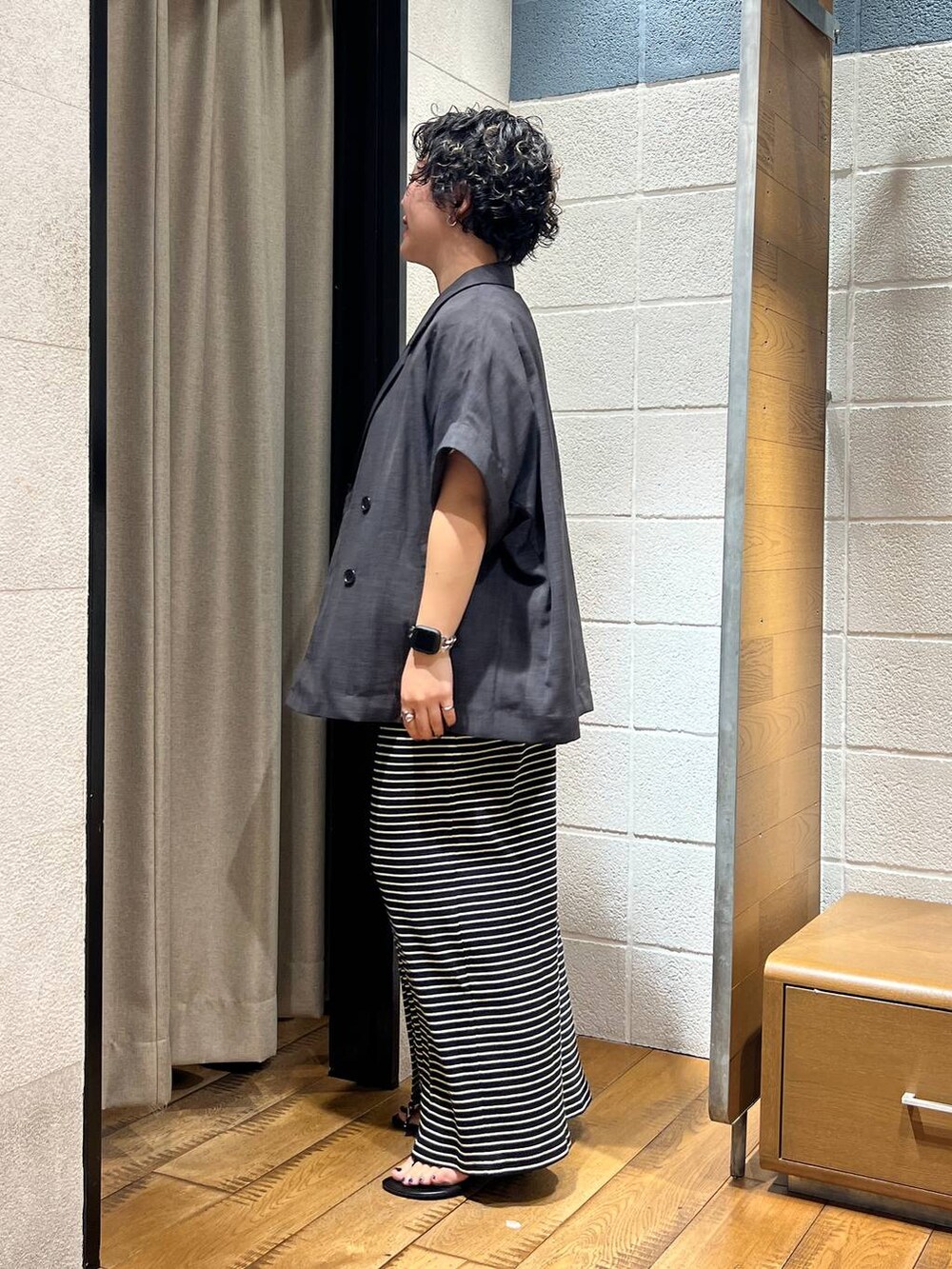 ブラック系のスカート、ブラック系のサンダル、ベージュ系のTシャツ/カットソーを着用したレディースの夏コーディネートの2枚目の写真
