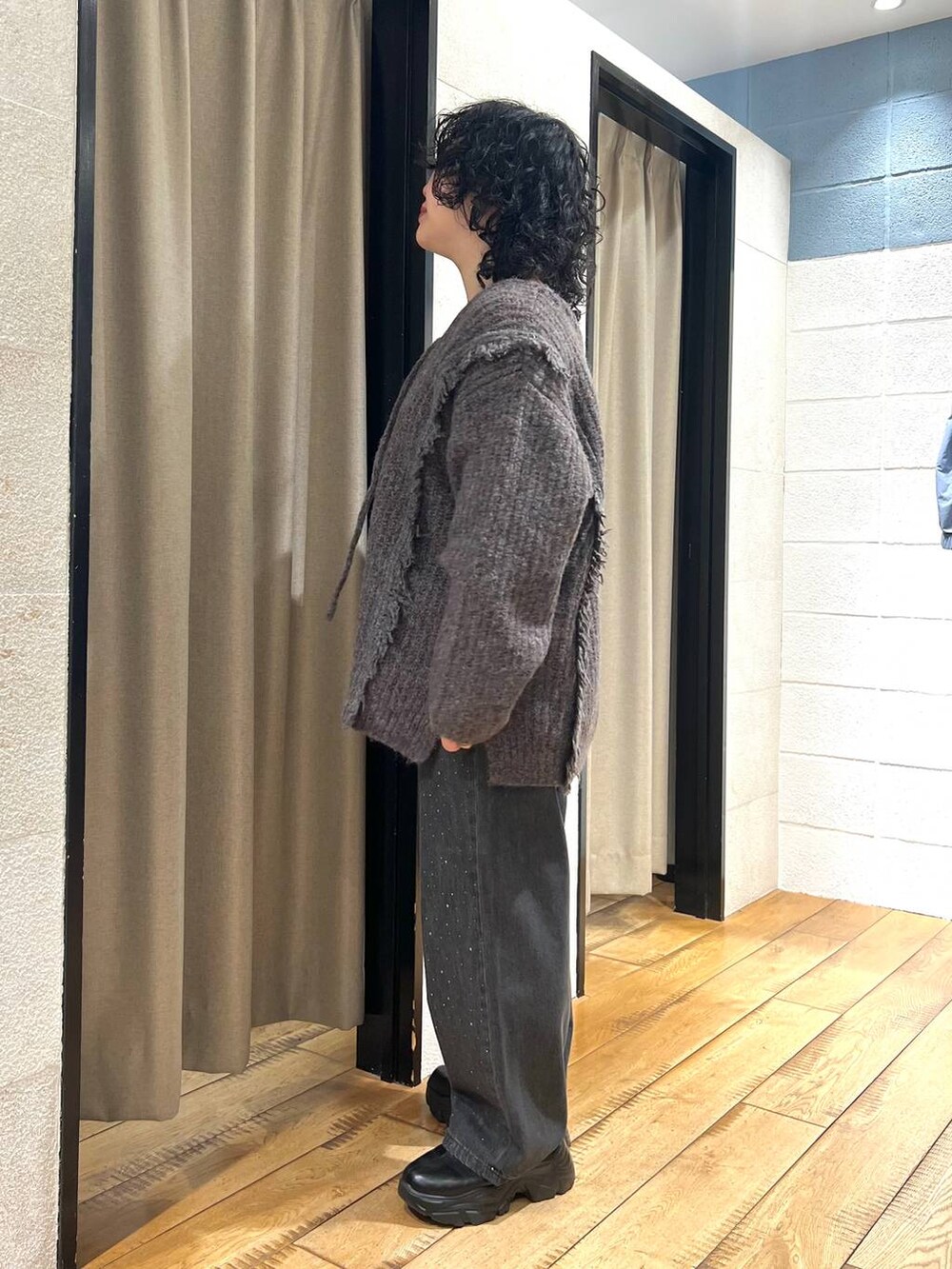 グレー系のニット/セーター、ブラック系のデニムパンツ、ブラック系のブーツを着用したレディースの秋コーディネートの4枚目の写真