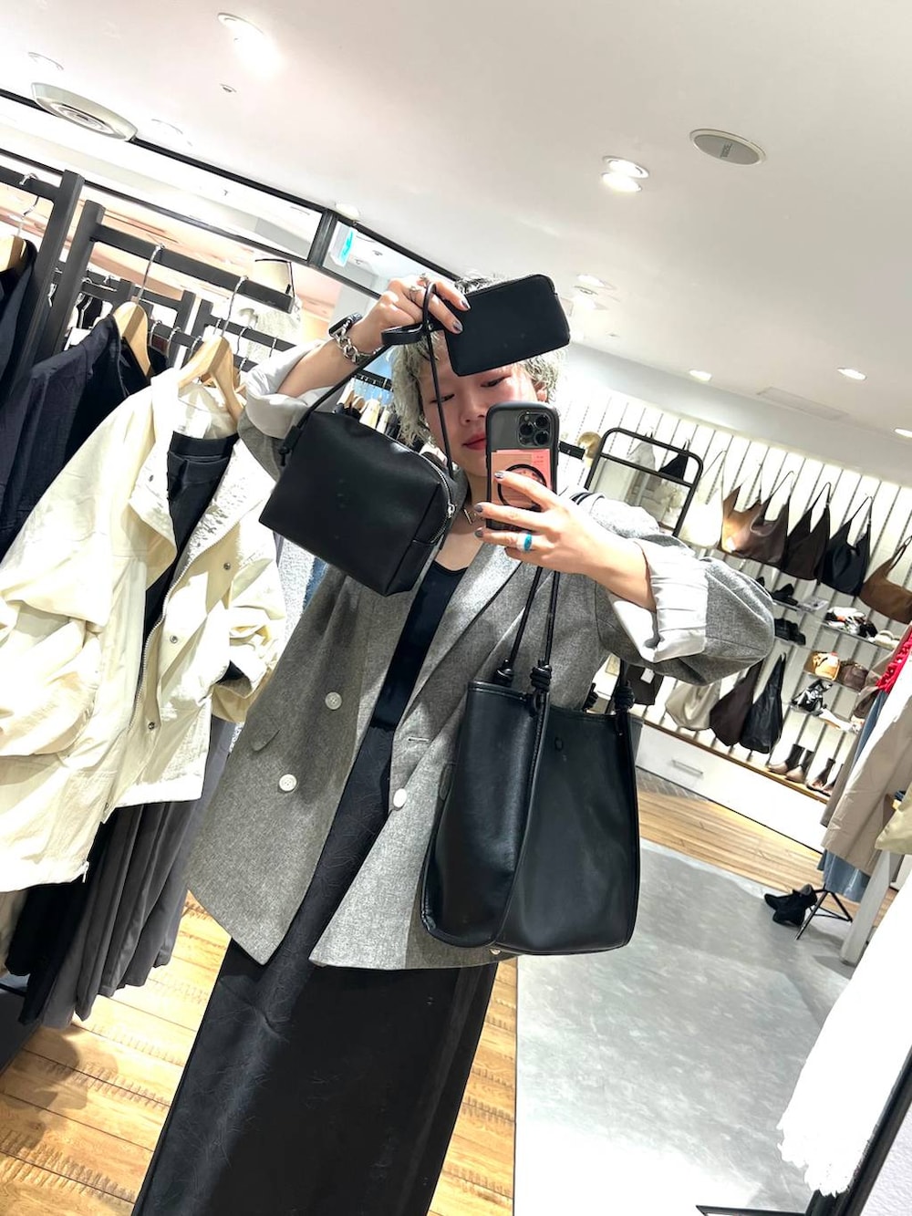 ブラック系のスカート、ブラック系のトートバッグ、グレー系のテーラードジャケットを着用したレディースの春コーディネートの2枚目の写真