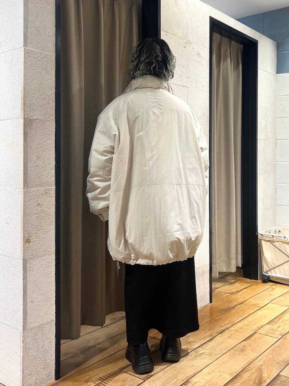 ブラック系のブーツ、ホワイト系のブルゾン、グリーン系のニット/セーターを着用したレディースの冬コーディネートの3枚目の写真