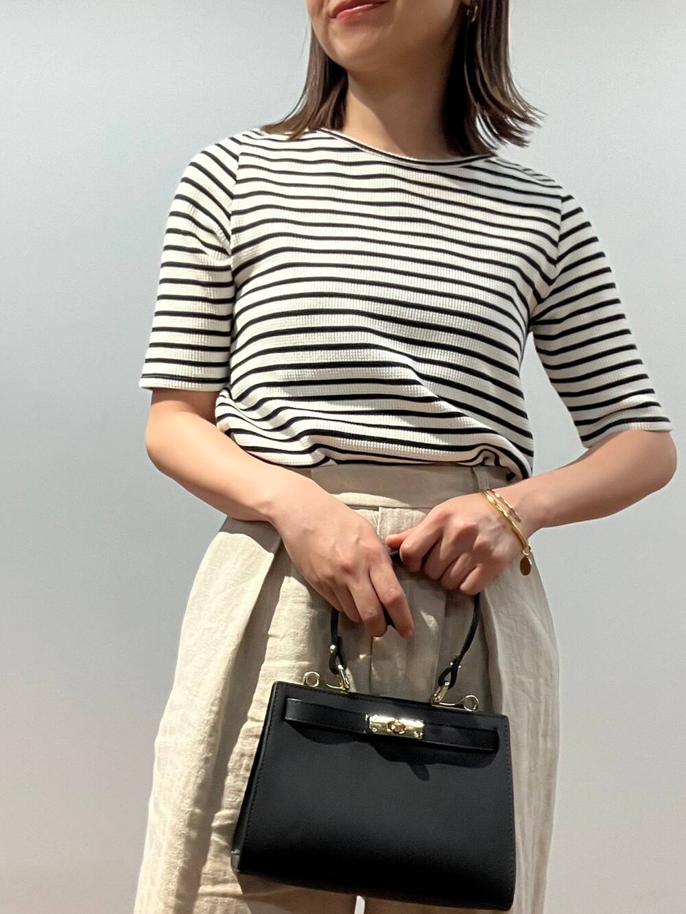 ホワイト系のTシャツ/カットソー、ベージュ系のその他パンツ、ブラック系のショルダーバッグを着用したレディースの春コーディネートの5枚目の写真