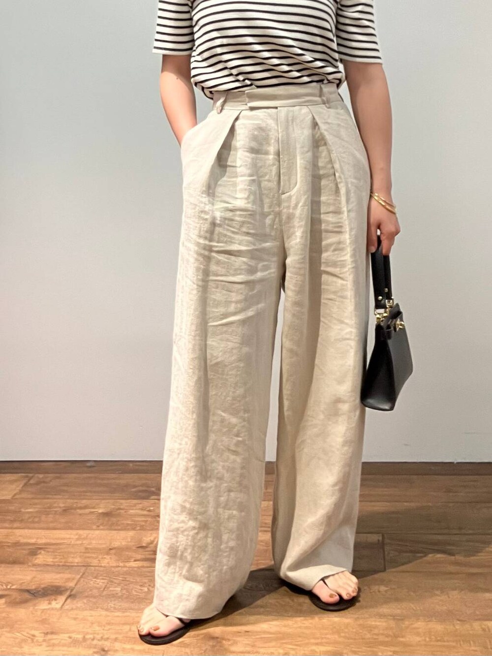 ホワイト系のTシャツ/カットソー、ベージュ系のその他パンツ、ブラック系のショルダーバッグを着用したレディースの春コーディネートの6枚目の写真