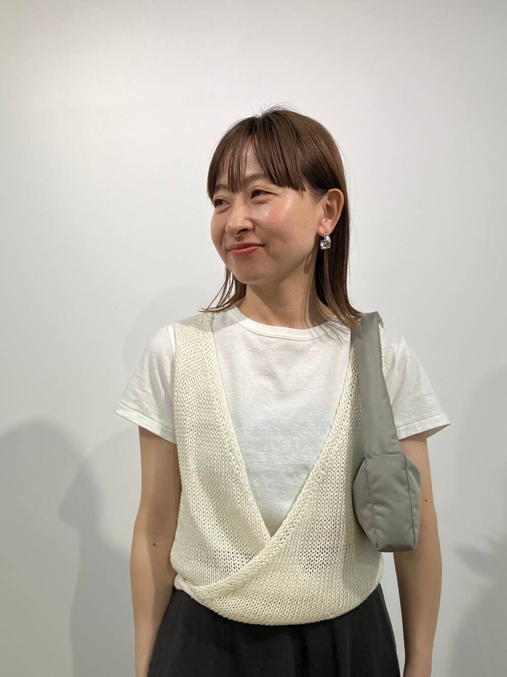 グリーン系のショルダーバッグ、グレー系のスカート、ホワイト系のTシャツ/カットソーを着用したレディースの春コーディネートの5枚目の写真