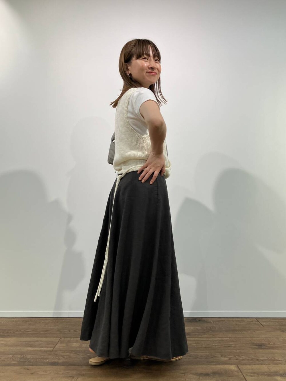 グリーン系のショルダーバッグ、グレー系のスカート、ホワイト系のTシャツ/カットソーを着用したレディースの春コーディネートの2枚目の写真